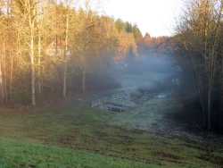 Vom großen Staudamm aus sieht man in das Tal des Orrotbaches, der in die Richtung zur Jagst fließt. Das Tal ist eng. Nebelschwaden liegen über dem Tal im Dezember 2015.