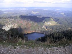 vomGipfel des Seebucks sieht man den Feldbergsee. Er leuchtet tief blau und ist umgeben von Nadelwald.