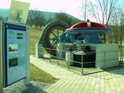 beim Krafthaus ist eine restaurierte Wasserkraftmaschine zu sehen. Eine Anzeigetafel informiert über die aktuelle Stromgewinnung.